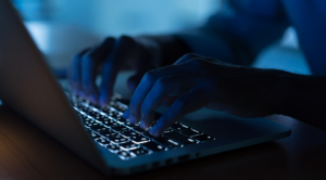 person typing on keyboard in the dark